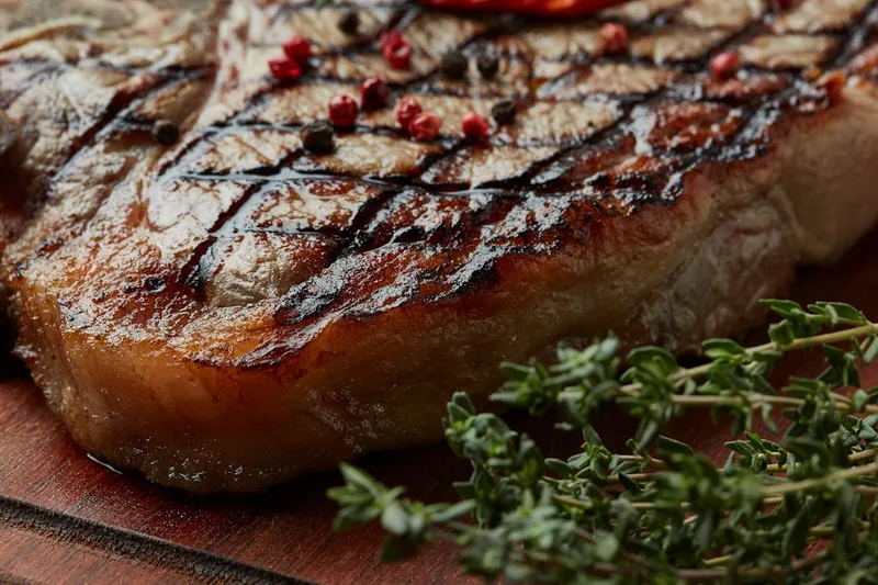 Ein perfekt gegrilltes Steak mit krosser Kruste auf einem Holzbrett, Ergebnis des Oberhitzegrills.
