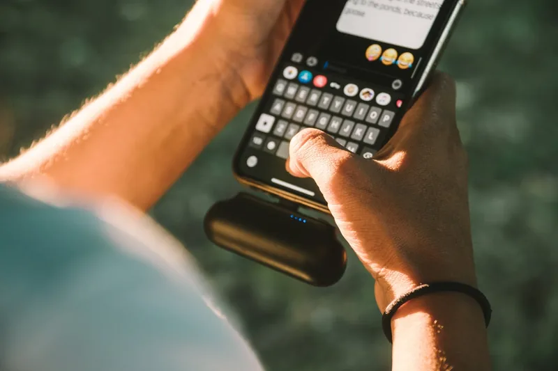 Eine Person lädt ihr Smartphone mit einer Outdoor-Powerbank beim Wandern in den Bergen auf.