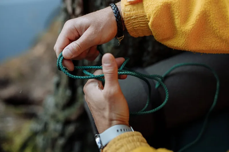 Eine Person bindet einen stabilen Paracord-Knoten, demonstriert eine Grundtechnik für Sicherheit.