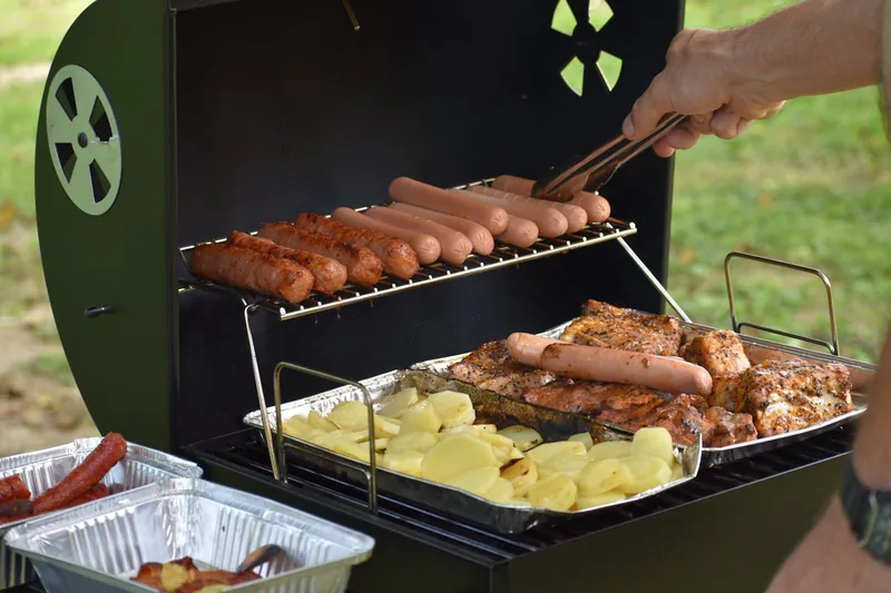 Entspannte Grillparty im Garten mit saftigem Räucherfleisch vom Pelletgrill und fröhlichen Menschen.