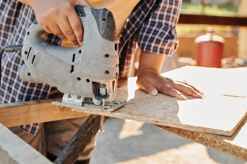 Handwerker sägt mit einer Pendelhubstichsäge präzise eine Rundung in ein Holzbrett.