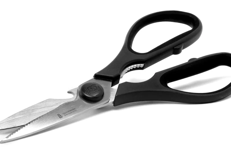 Nahaufnahme der scharfen Klinge und des ergonomischen Griffs einer Pizzaschere, Fokus auf Material.