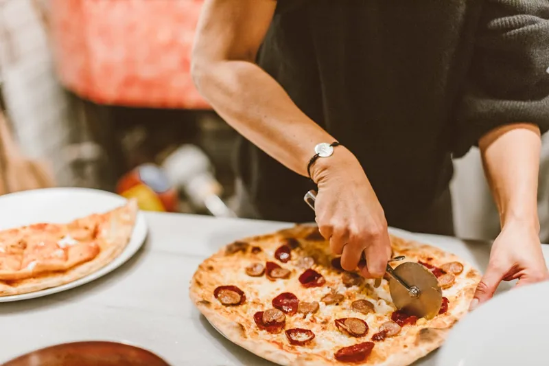 Detaillierte Nahaufnahme der rostfreien Klinge und des robusten Griffs eines Pizzaschneiders, Fokus Material.
