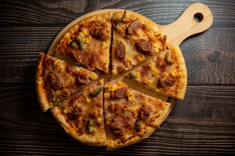 Appetitlich angerichtete Pizzastücke auf einem Holzbrett, Indikator für gelungenen Genuss zu Hause.