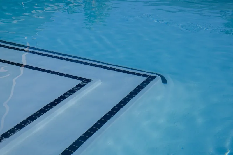 Ein sauberer, reparierter Pool mit klarem Wasser an einem sonnigen Tag, bereit zum Baden und Schwimmen.