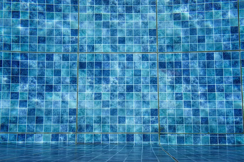 Ein Poolsauger reinigt den Boden eines Pools, während eine Hand ihn sanft steuert.