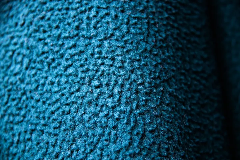 Nahaufnahme der hochwertigen Wolltextur und des Leder-Schirms einer Prinz-Heinrich-Mütze, Material-Detail.