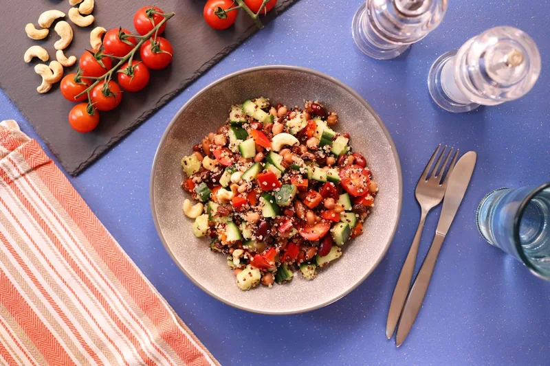 Ein fertig zubereiteter Quinoa-Salat mit frischen Zutaten, appetitlich angerichtet auf einem Holztisch.