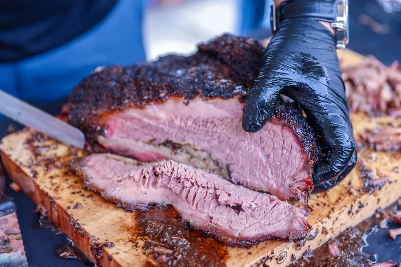 Rustikale Gartenszene mit einem Smoker, geschnittenem Brisket und gemütlicher Atmosphäre im Hintergrund.