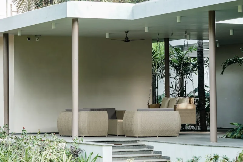 Idyllische Gartenszene mit einem stilvollen Rattan-Loungeset auf einer Terrasse, lädt zum Verweilen ein.