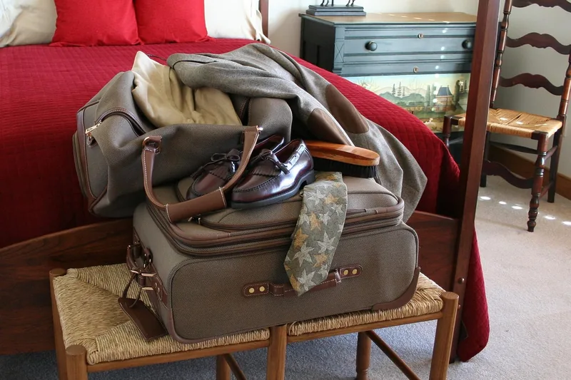 Mehrere verschiedene Reisetaschen stehen oder liegen in einem aufgeräumten Hotelzimmer, bereit für die Reise.