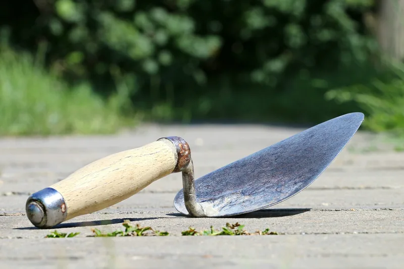 Eine Hand trägt Reparaturspachtel mit einem Spachtel auf eine beschädigte Oberfläche auf.
