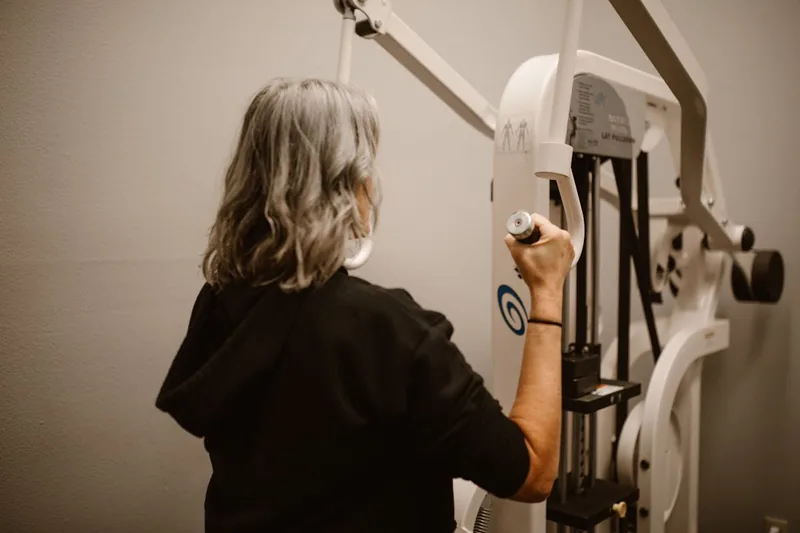 Eine Person nutzt eine Riemenscheibe als Teil eines Kraftsport-Trainingsgeräts im Fitnessstudio.