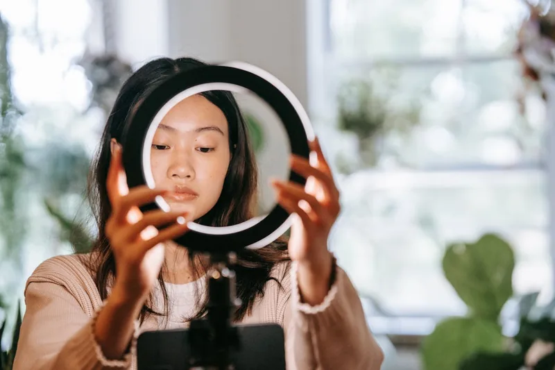 Ein aufgeräumtes Heimstudio mit Ringlicht im Hintergrund, das zu professionellen Videoaufnahmen führt.