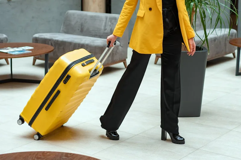 Aufgeklappter Rollkoffer in einem hellen Hotelzimmer, daneben eine Reisetasche, Symbol für Urlaub.