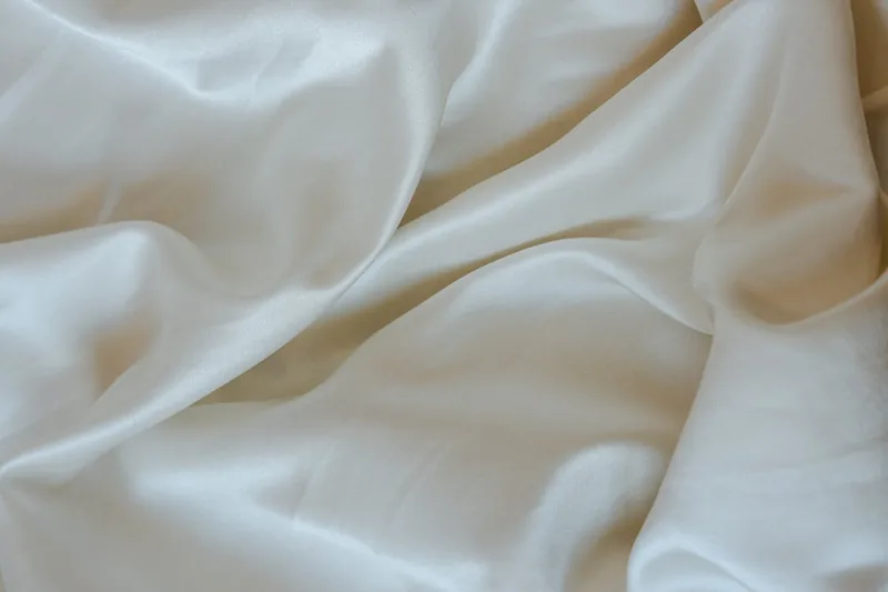 Elegante Satin Bettwäsche, glatt und glänzend, sorgfältig gefaltet oder ausgebreitet für den Verkauf.