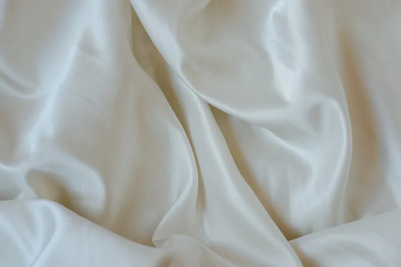 Nahaufnahme der glatten, schimmernden Oberfläche von hochwertiger Satin Bettwäsche, die den Glanz zeigt.