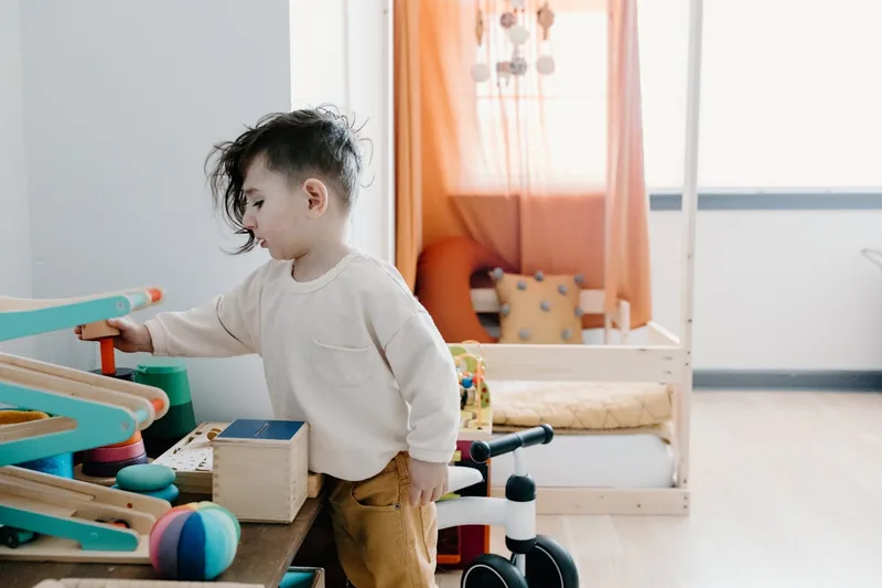 Ein helles Kinderzimmer mit verschiedenen Holzspielzeugen, darunter ein Schiebetier, das zum Spielen einlädt.