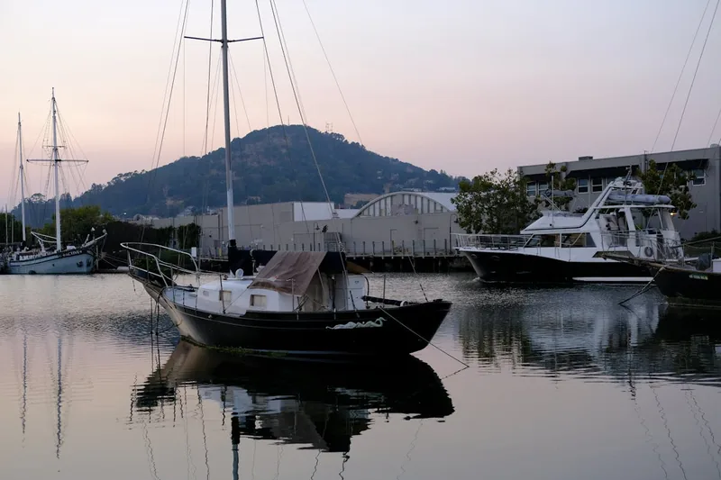 Eine idyllische Hafenszene mit festgemachten Segelbooten bei Sonnenuntergang, die Ruhe ausstrahlt.