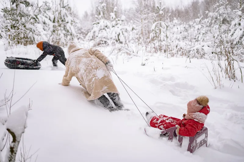 Eine idyllische Winterlandschaft mit Kindern, die sicher in ihren Schneeanzügen im Schnee toben.