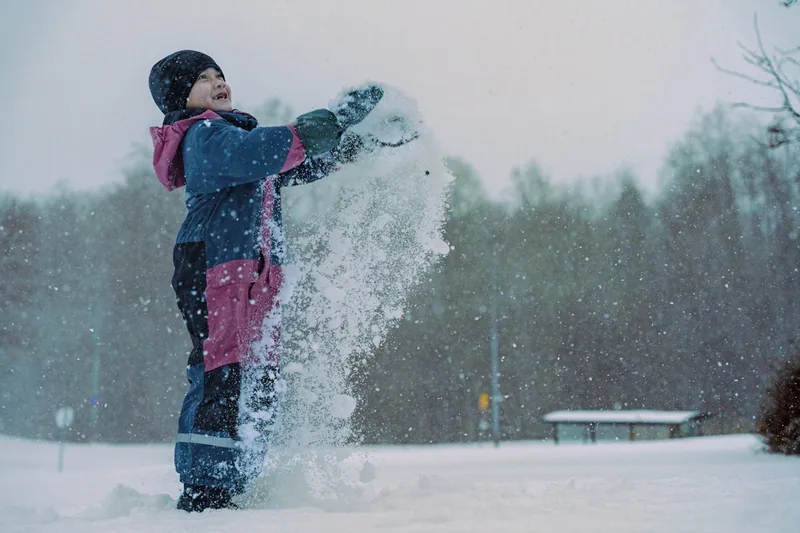 Ein Kind zieht oder verstellt seine Schneehose für Kinder, bereit für den aktiven Tag im Schnee.