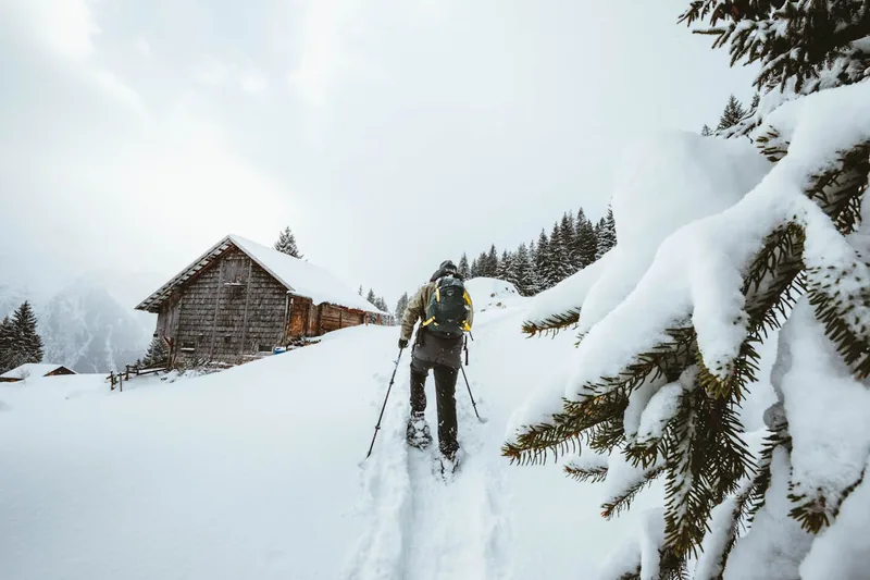 Eine Person wandert mit Schneeschuhen durch tiefen Schnee, von hinten gesehen.