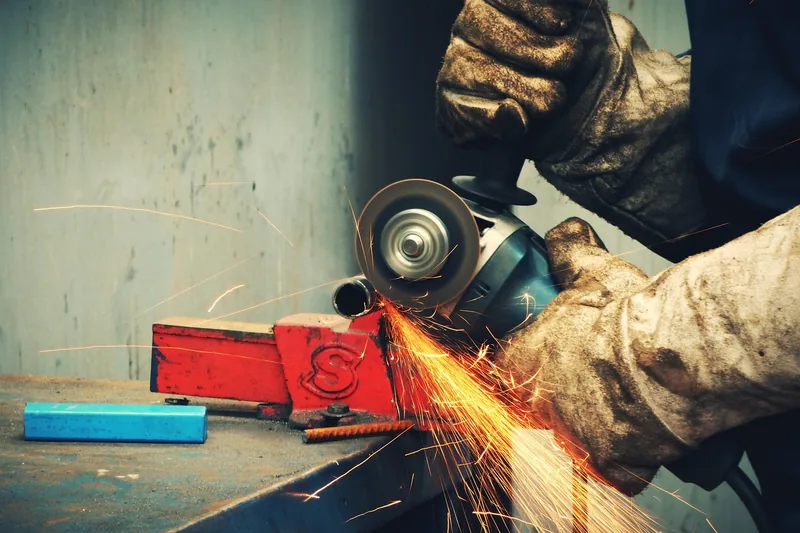 Eine Person, die Schnittschutzhandschuhe bei präzisen Arbeiten in einer Werkstatt trägt, fokus auf Anwendung.