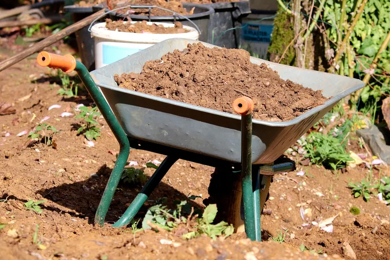 Eine Person transportiert mit einer stabilen Schubkarre Erde in einem Garten, praktische Anwendung.