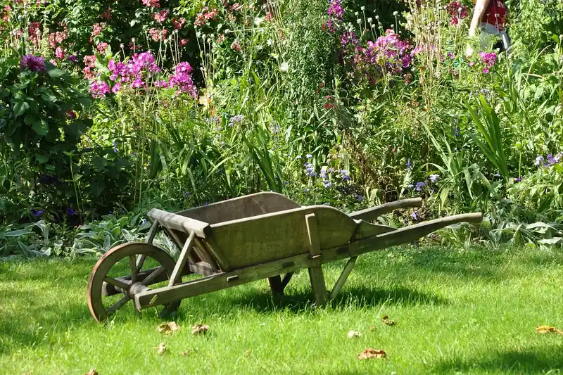 Ein frisch angelegtes Blumenbeet mit Gartengeräten im Hintergrund, inklusive einer Schubkarre, symbolisiert erfüllte Gartenarbeit.