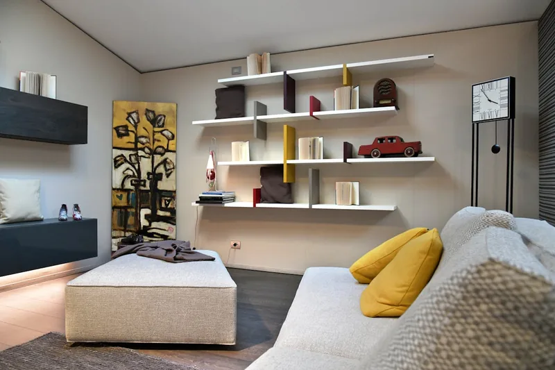 Ein modern eingerichtetes Wohnzimmer mit einem Schweberegal, das Bücher und Dekorationen trägt.