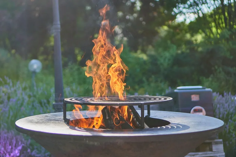Gemütliche Grillparty-Atmosphäre im Abendlicht mit Freunden und Familie; Schwenkgrill im Hintergrund.