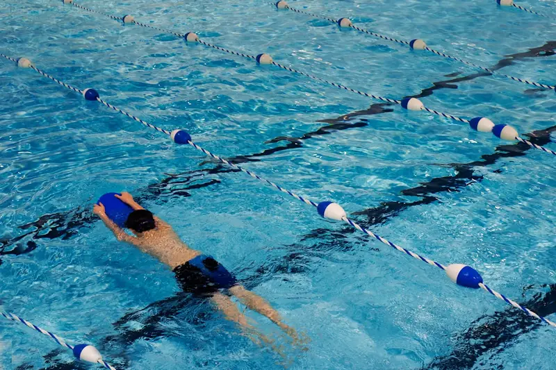 Eine Person nutzt ein Schwimmbrett im Pool, um die Beintechnik und den Auftrieb zu trainieren.