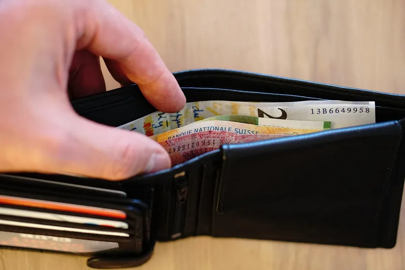 Eine Person bezahlt mit einem schlanken Wallet, die Hand hält das Produkt beim Auswählen einer Karte.