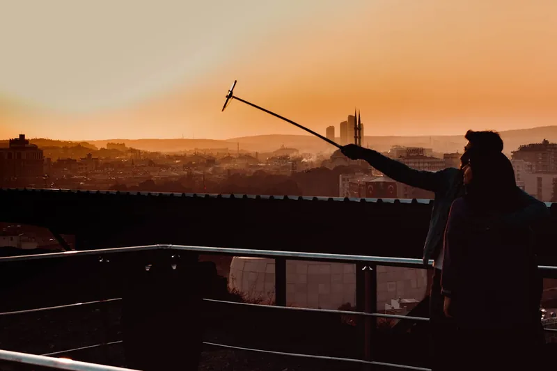 Eine Person benutzt einen Selfie-Stick mit Smartphone, um ein Foto von sich und der Landschaft zu machen.
