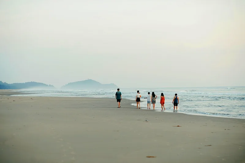 Eine Gruppe lachender Freunde genießt einen gemeinsamen Moment am Strand unter Palmen.