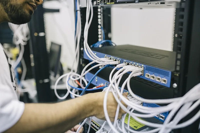 Eine Person installiert einen Server in einem Serverschrank, zeigt praktische Anwendung und Handgriffe.