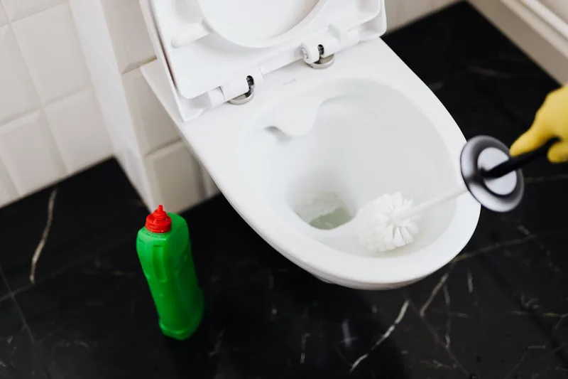 Eine Hand reinigt mit einer Silikon-Klobürste eine Toilette, demonstrierend die einfache Anwendung des Reinigungsprodukts.