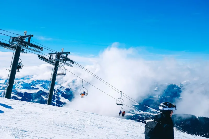 Panoramablick auf eine verschneite Berglandschaft mit Skifahrern im Hintergrund, die Skivergnügen genießen.