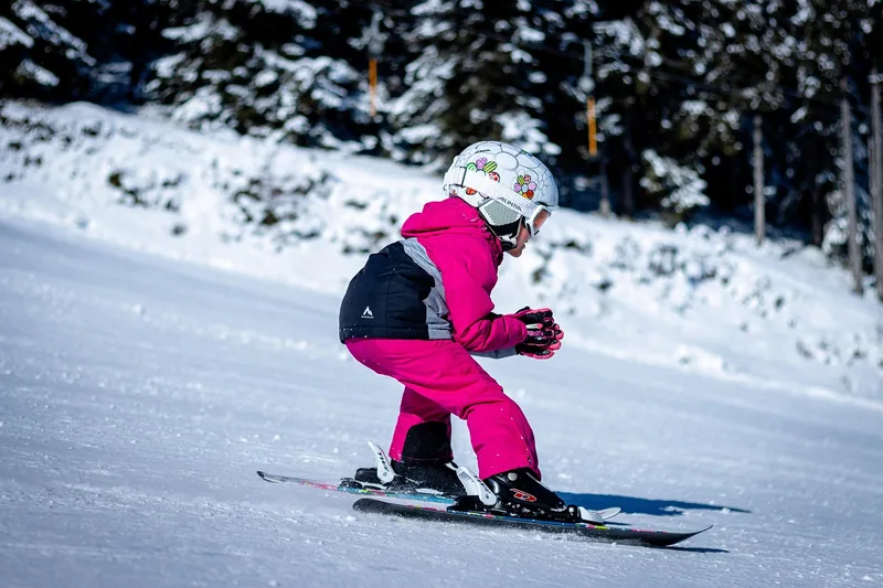 Kind beim Anziehen der Skibrille in Kombination mit einem Skihelm, Seitenansicht.