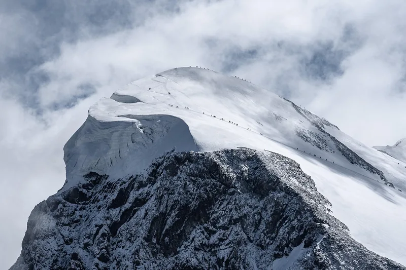 Ein Skitourengeher steigt mit Skifellen einen verschneiten Berghang hinauf, inmitten einer majestätischen Winterlandschaft.
