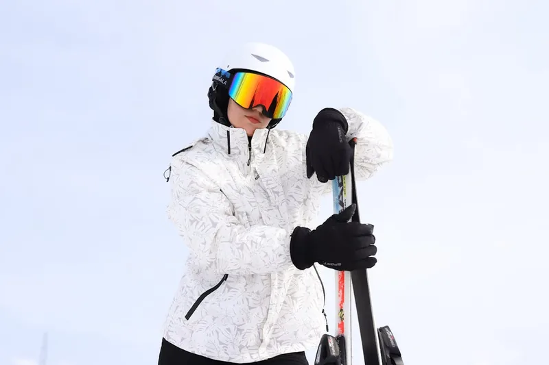 Ein Skifahrer im vollen Schwung, die Hand im Skihandschuh fest am Skistock haltend, im Schnee.