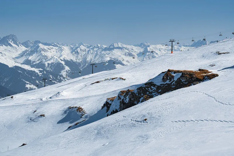 Malerische Winterlandschaft mit verschneiten Berggipfeln und einem Skigebiet im Hintergrund.