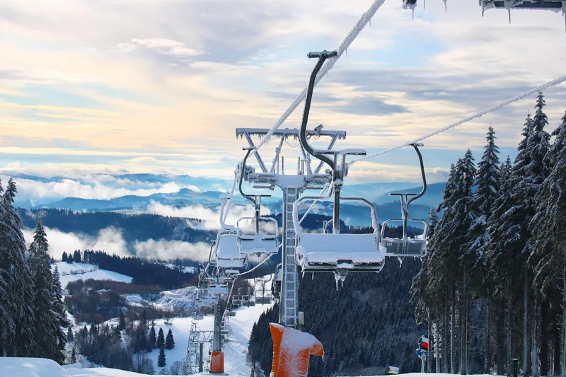 Panoramablick auf ein verschneites Skigebiet bei Sonnenuntergang, das zum Wintersport einlädt.