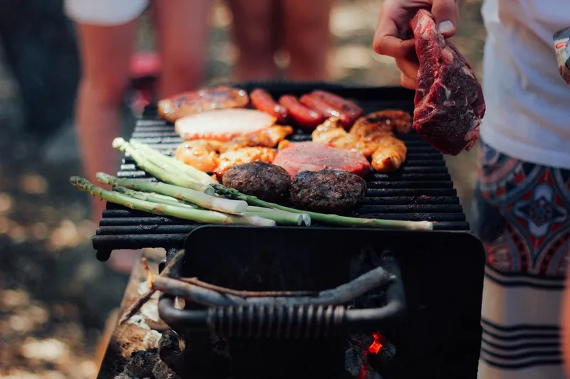 Eine idyllische Gartenszene mit Freunden, die saftiges, geräuchertes Grillgut genießen.