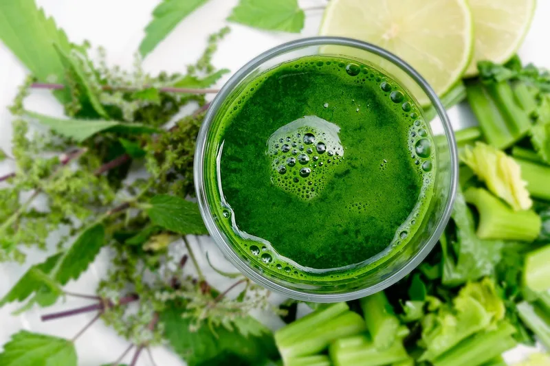 Ein frisch zubereiteter grüner Smoothie in einem Glas auf einer Küchenarbeitsplatte, gesunder Lifestyle.