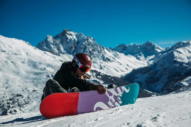 Eine Person befestigt den Snowboard-Boot in der Bindung auf der Piste, um für die Abfahrt bereit zu sein.