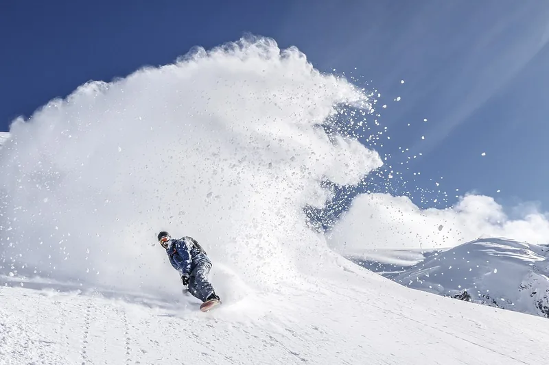 Atemberaubende Berglandschaft mit einem Snowboarder im Hintergrund, der die Freiheit genießt.