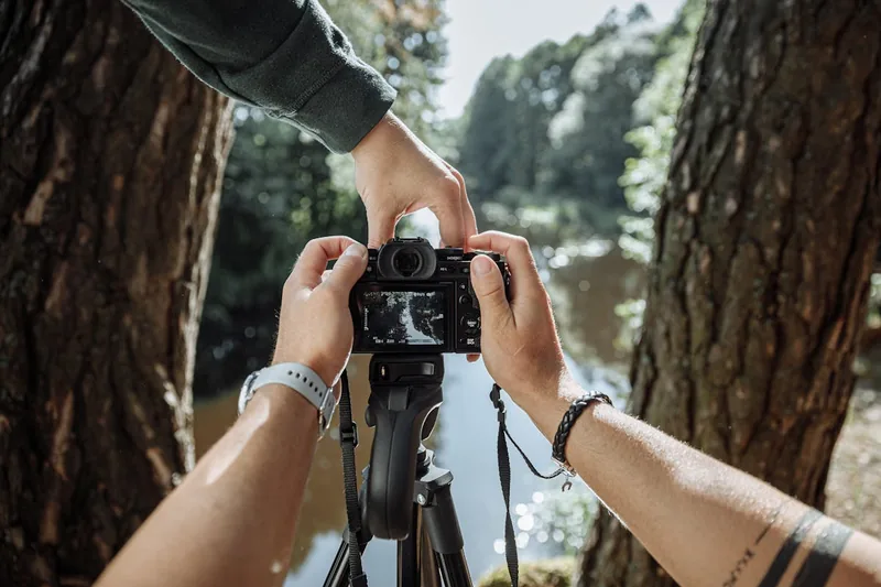 Eine Person nutzt eine spiegellose Kamera bei Tageslicht für Naturfotografie, Fokus auf Anwendung.