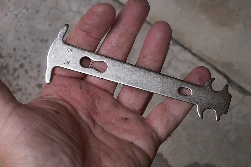 Ein hochwertiger Speichenschlüssel aus Metall, klar erkennbar vor neutralem Hintergrund, für präzise Fahrradwartung.