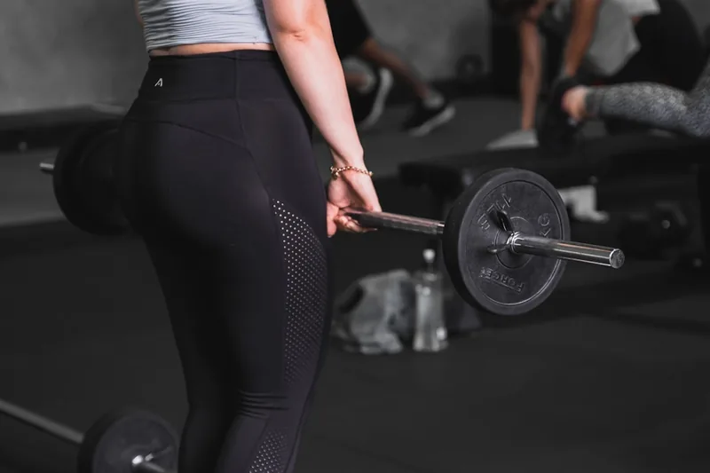 Eine Frau trainiert im Fitnessstudio, trägt eng anliegende Damen Sport Leggings und zeigt Bewegungsfreiheit.